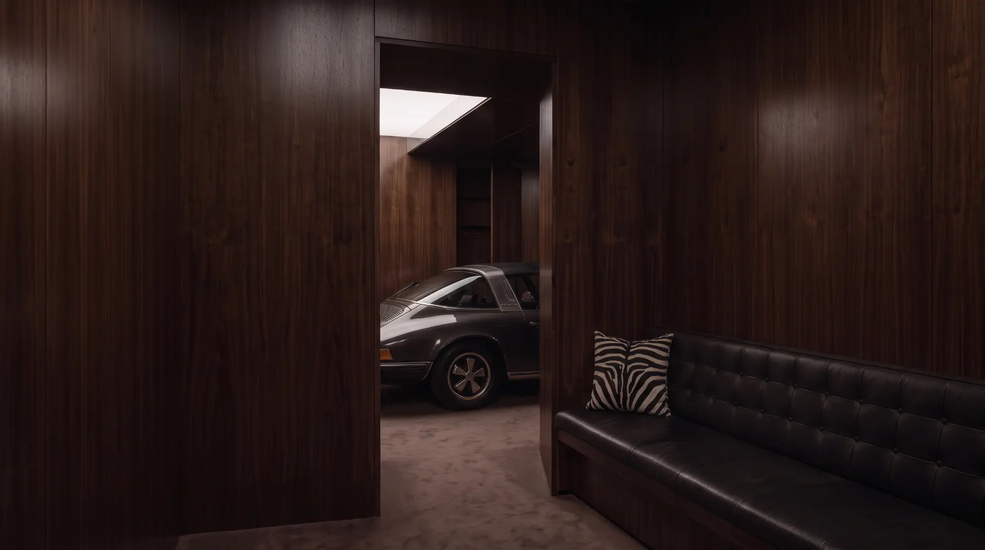 A dark walnut-panelled lounge with a leather bench and a classic Porsche in the garage beyond