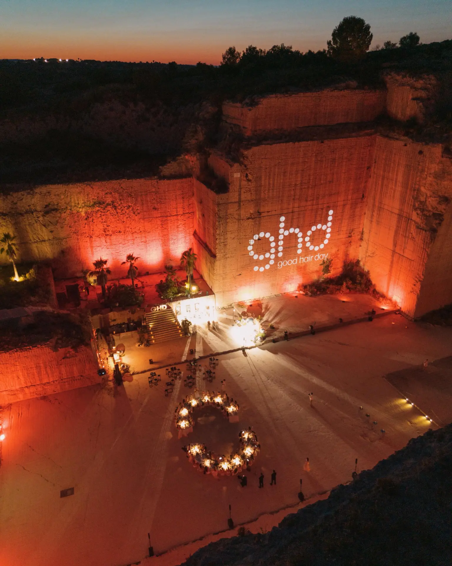 The ghd projection glowing on the quarry wall above the dinner tables at night in Sicily